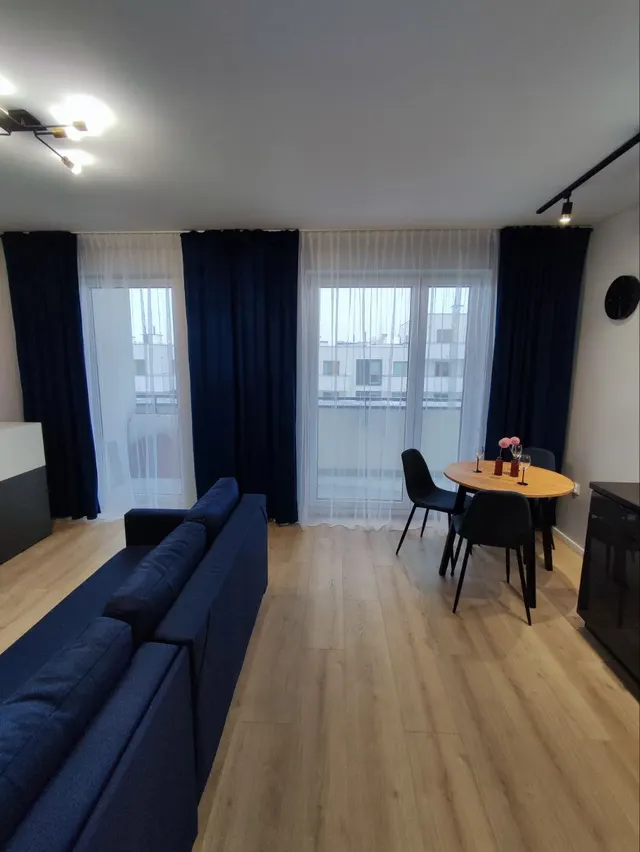 Salon z granatową sofą, zasłonami w tym samym kolorze i strefą jadalną przy oknie