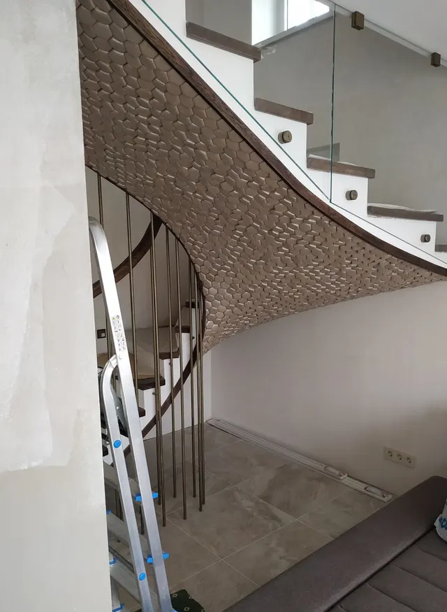 Zabudowa schodów wyłożona łuskową mozaiką, z drewnianym obrzeżem i szklaną balustradą
